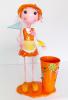 arm196 ตุ๊กคาสังกะสี เด็กหญิงชุดเดรสสีส้ม ถือไม้จับแมลง เล่นกับผีเสื้อ ยืนข้างถังทรงสูง